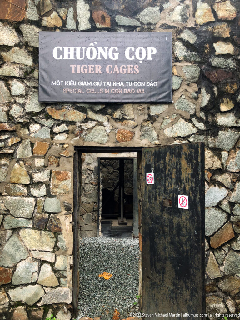 Stone doorway with a bilingual Tiger Cages sign above the entrance.