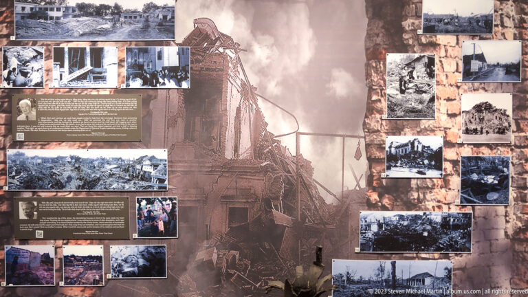 Sepia museum panel with archival photographs of bomb damage and ruined buildings.