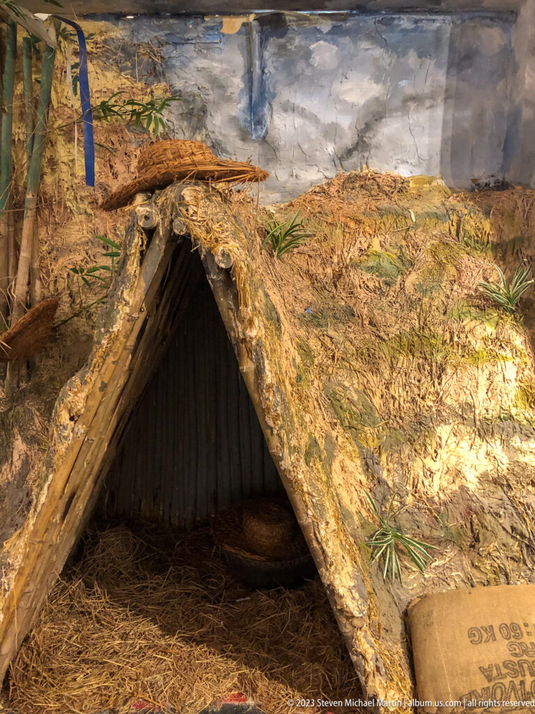 Low camouflaged bunker with timber entrance, straw, and earth covering.
