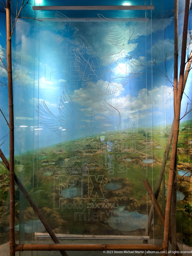 Immersive landscape with bare tree trunks, painted countryside, and peace graphics.