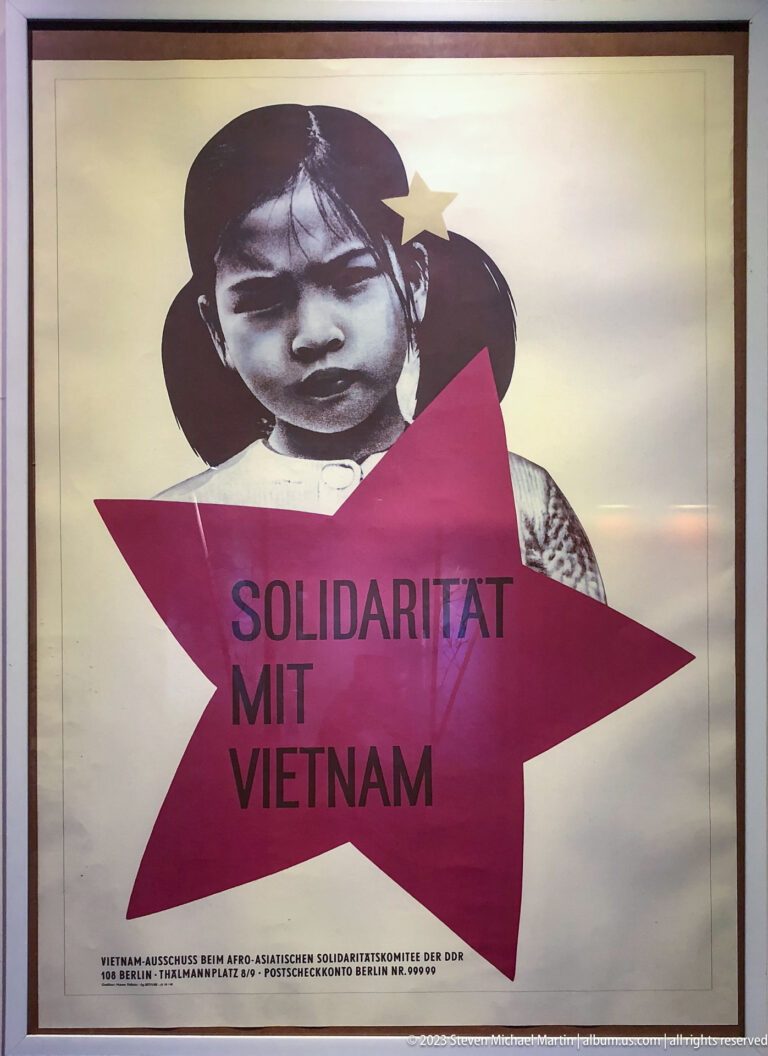German poster with a child’s portrait, red star, and text “Solidarität mit Vietnam.”
