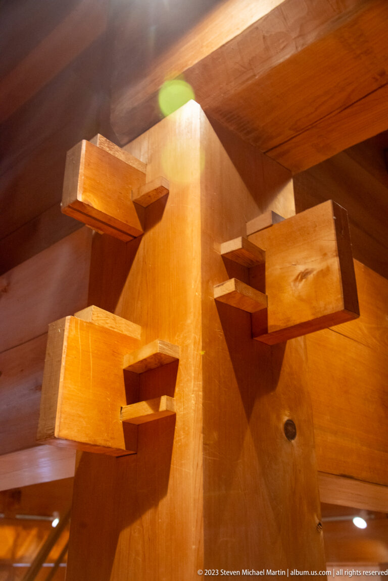 Large timber post with multiple interlocking beams and fitted wooden blocks in an indoor display.