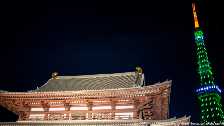 Zōjō-ji’s large wooden gate in foreground with illuminated Tokyo Tower behind.