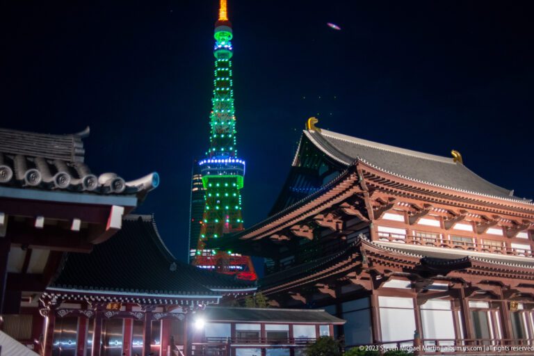 Illuminated Zōjō-ji buildings frame Tokyo Tower at night.