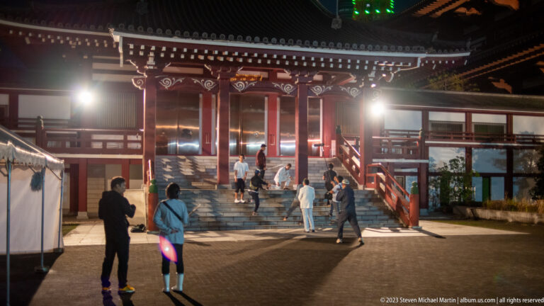 Visitors walk toward an illuminated red temple hall in the Zōjō-ji courtyard at night.
