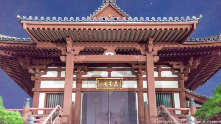 Frontal night view of a large red-and-white Zōjō-ji temple hall with deep tiled eaves.