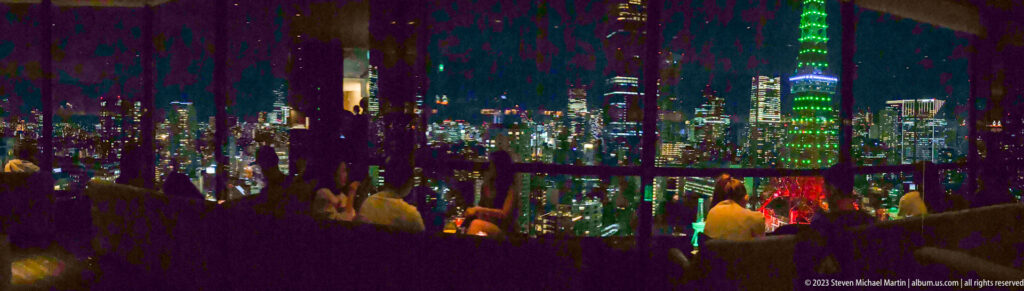 Tokyo Tower and city lights appear through dark reflections around seated lounge guests.