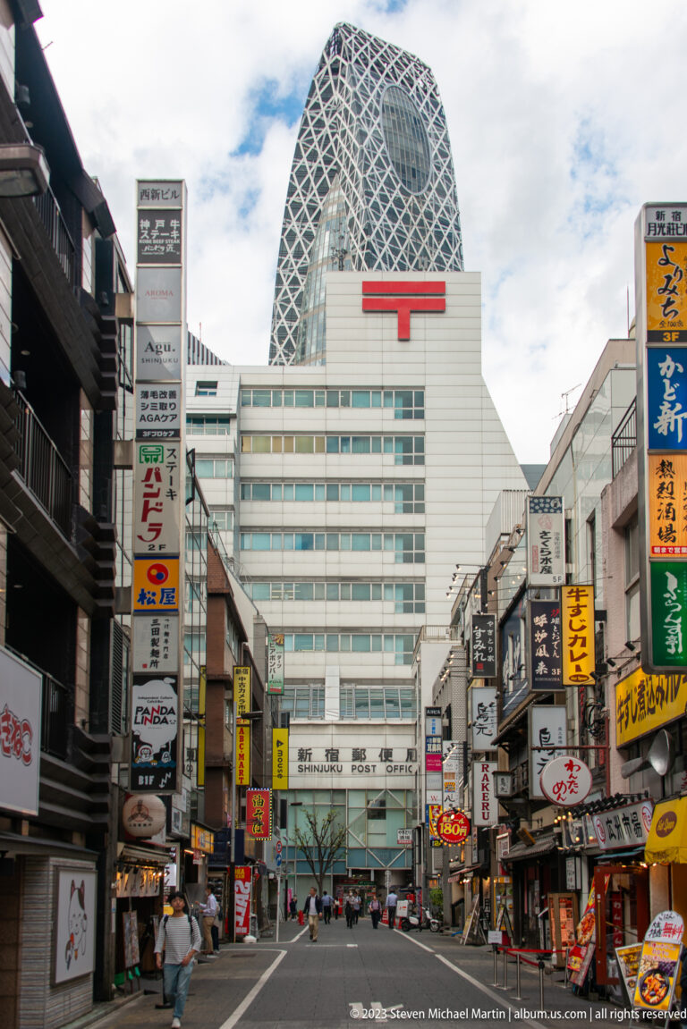 Mode Gakuen Cocoon Tower rises behind a large building with a red Japan Post symbol.