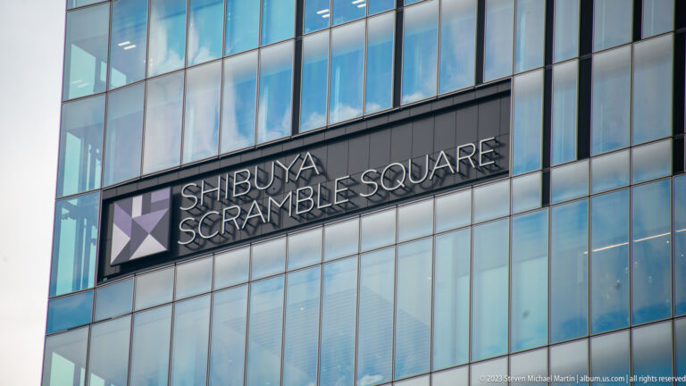 Shibuya Scramble Square name and geometric logo mounted on a blue glass façade.