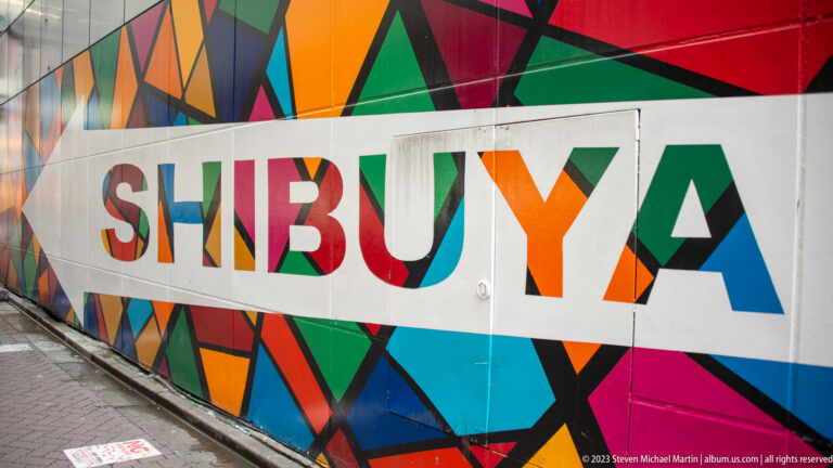Angled close view of multicolored geometric panels spelling Shibuya along a sidewalk.