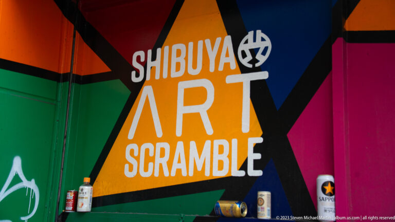 Colorful wall mural reads Shibuya Art Scramble above several spray cans.