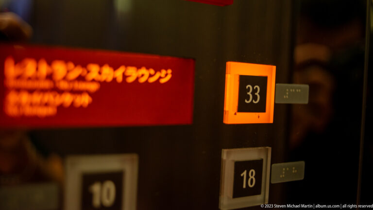 Illuminated elevator floor indicators show 33, 18, and 10 in a dark warm-toned interior.
