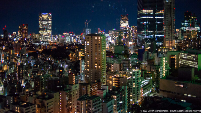 High-rise Tokyo district at night with dense buildings and illuminated windows.
