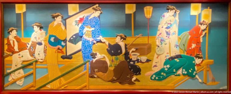 Women in kimono, seated workers, and porters carrying goods fill a busy bridge or street scene.
