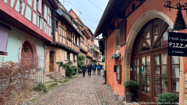 Pedestrians walk a cobbled lane past the arched entrance and sign of I Soliti Ignoti restaurant.