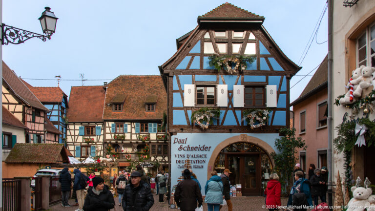 Paul Schneider Vins d’Alsace shop in a blue-and-white half-timbered house with visitors and Christmas decorations.
