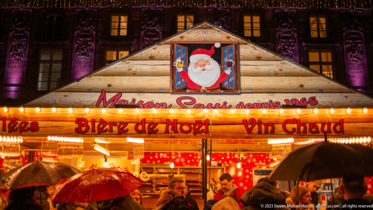 Maison Saur Christmas chalet advertising Bière de Noël and Vin Chaud, with umbrellas and Santa decoration.