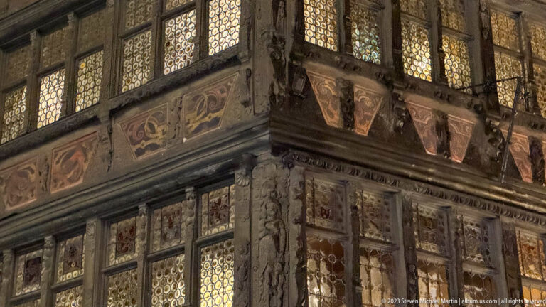 Close view of Maison Kammerzell’s carved timber framing, painted panels, and patterned leaded windows.