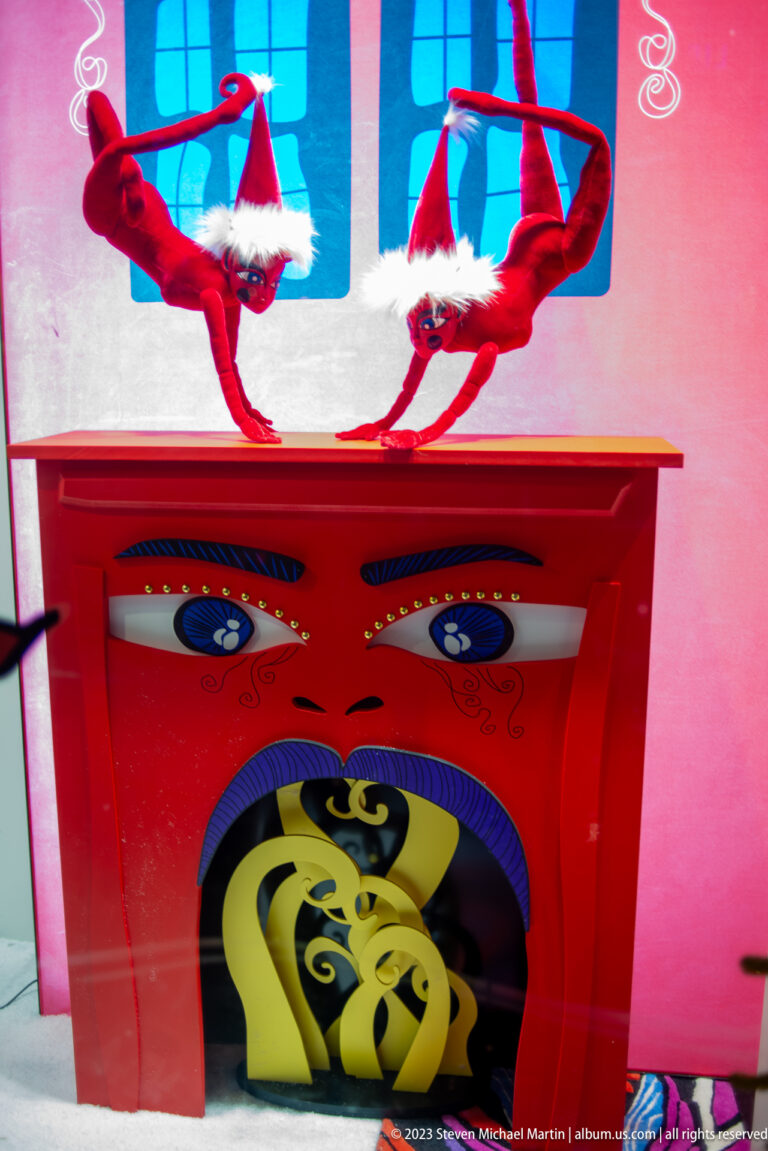 Close view of a red illustrated cabinet with painted eyes and upside-down red holiday figures above.