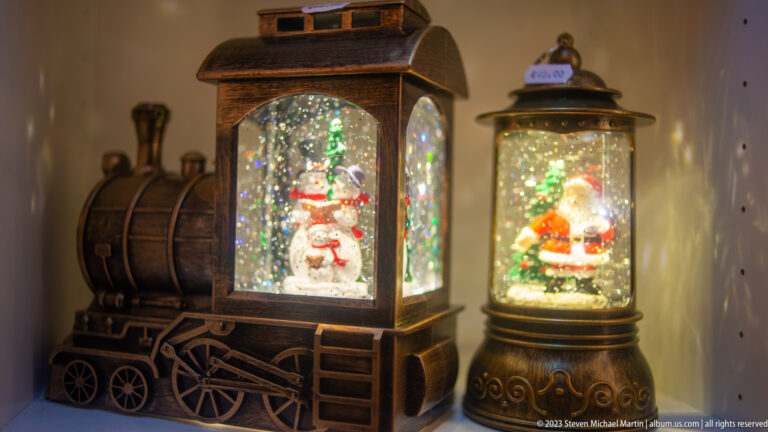 Locomotive- and lantern-shaped Christmas snow globes containing a snowman and Santa Claus with glittering light.
