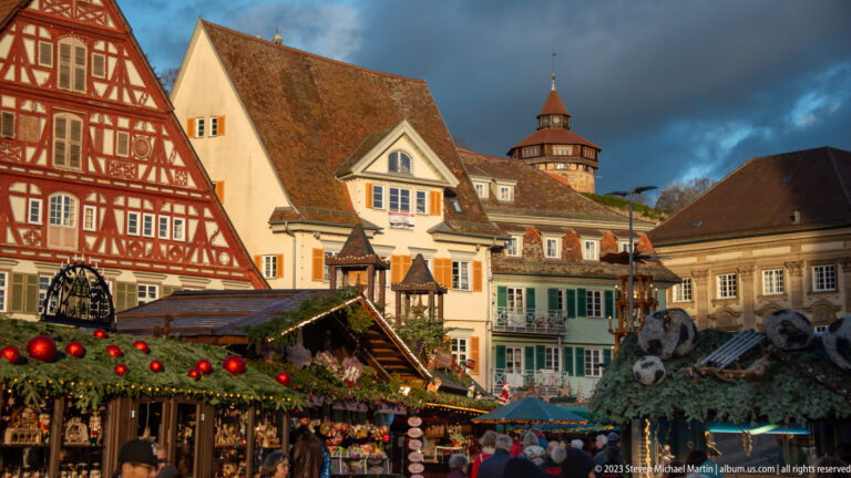 Christmas market stalls and historic houses with a tower of Esslinger Burg rising on the hillside behind.