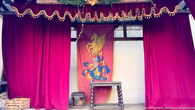 Empty stage with red curtains, heraldic banner, wooden table and stool at Esslingen's medieval market.