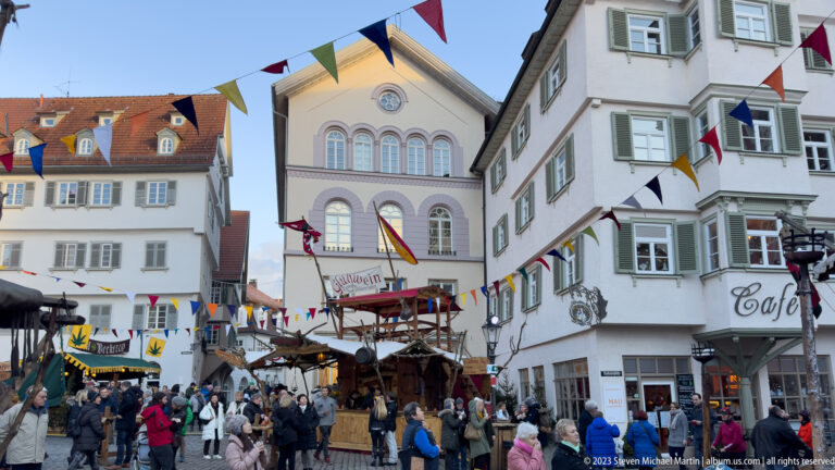Crowded Esslingen market street with wooden stalls, colorful pennants and historic façades near the Altes Rathaus.