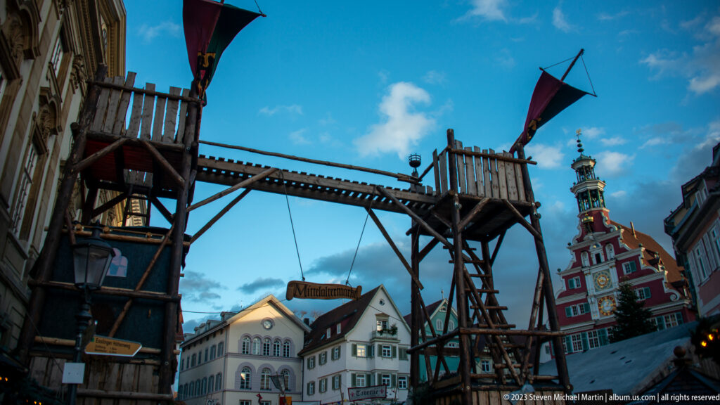 Temporary timber gateway with platforms and flags standing before the red clock façade of the Altes Rathaus.