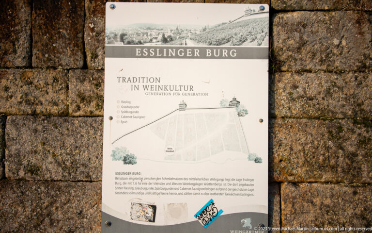 Interpretive sign titled Esslinger Burg and Tradition in Weinkultur mounted on a rough stone wall, with map and German text.