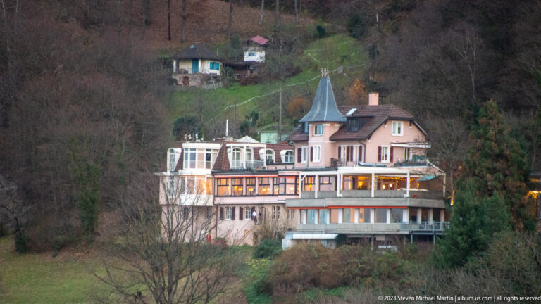 Large pale villa with enclosed verandas and a small turret on a wooded hillside above Freiburg.