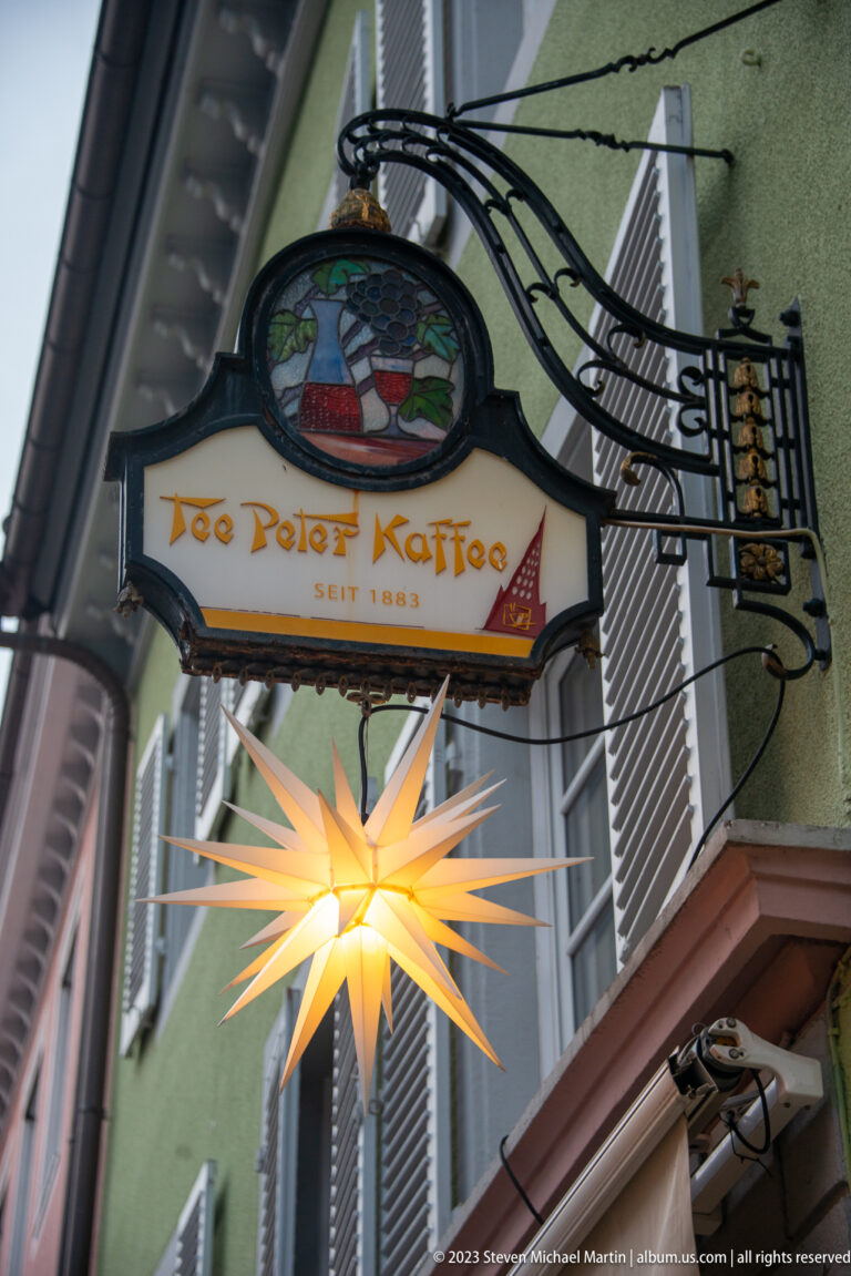 Hanging sign reading Zum Roten Käfig above a glowing many-pointed star on a Freiburg building façade.