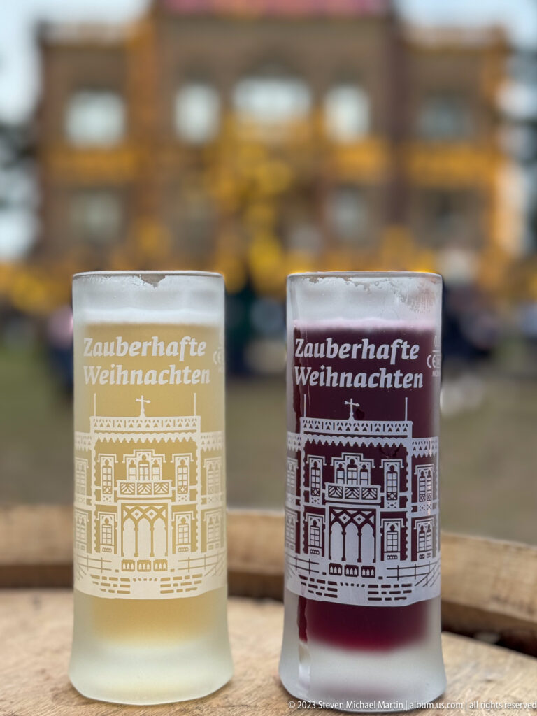 Two frosted Freiburg Christmas-market glasses, one pale and one red, printed with “Zauberhafte Weihnachten” and an architectural motif.
