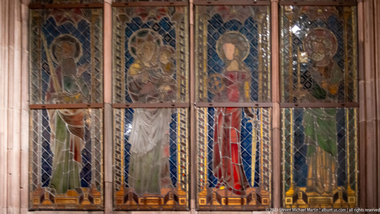 Four narrow stained-glass panels with standing haloed figures in Freiburg Minster.