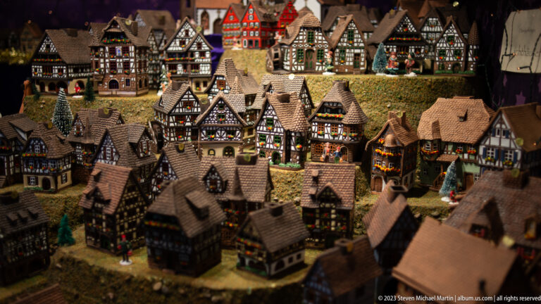 Miniature Christmas village filled with detailed half-timbered houses, steep roofs, tiny streets, and small figures.