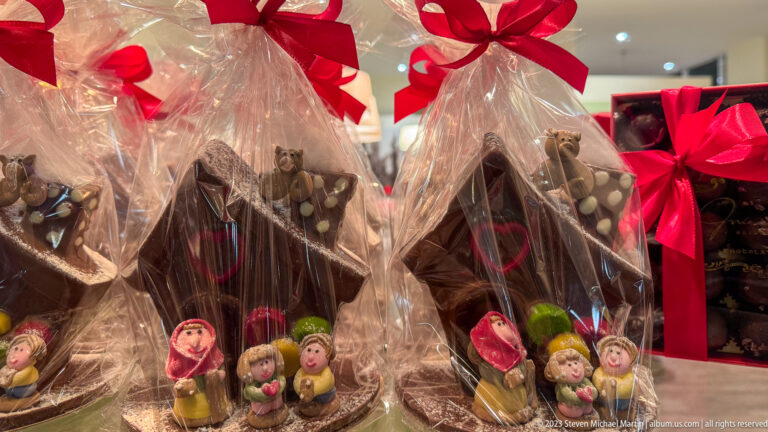 Cellophane-wrapped chocolate holiday figures tied with red bows, with smaller colorful chocolate figures in front.