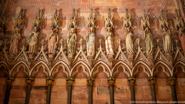 Close view of slender Gothic stone figures standing above pointed niches on Freiburg Minster’s portal.