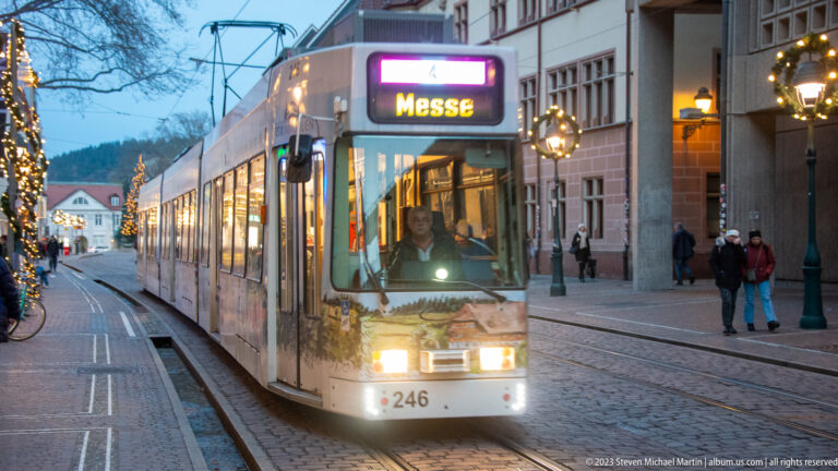 Freiburg tram number 246 approaches on street tracks with Messe displayed above the windshield and festive garland on the front.