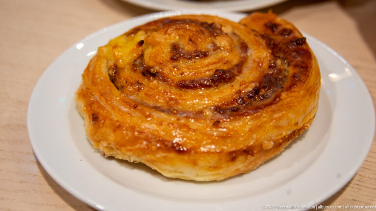 Golden-brown glazed spiral pastry with crisp layered edges on a small white plate.