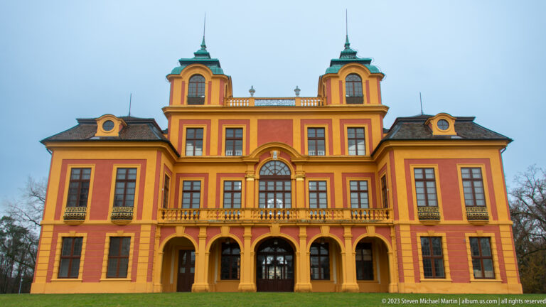 Front elevation of Schloss Favorite with central arched window, arcades, paired roof towers, and red-and-ocher walls.
