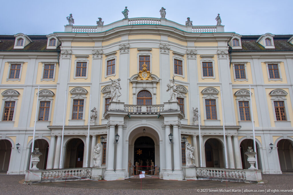 Frontal view of the ornate central entrance pavilion at Ludwigsburg Residential Palace with columns, statues, and gilded crest.