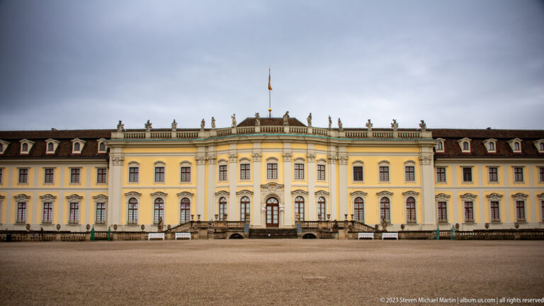 Wide frontal view of Ludwigsburg Residential Palace garden façade with central stairs, rooftop statues, and flag.