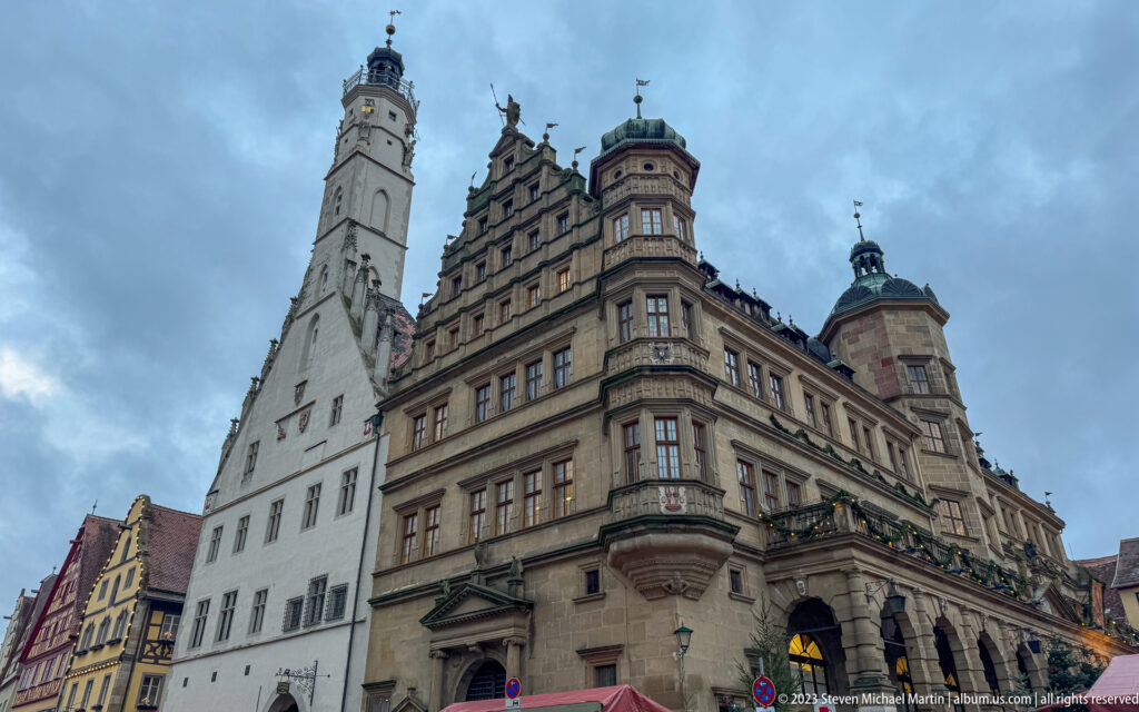 Low-angle view of Rothenburg Town Hall with pale Gothic façade, ornate Renaissance wing, tower, arcades, gables, and corner turrets.
