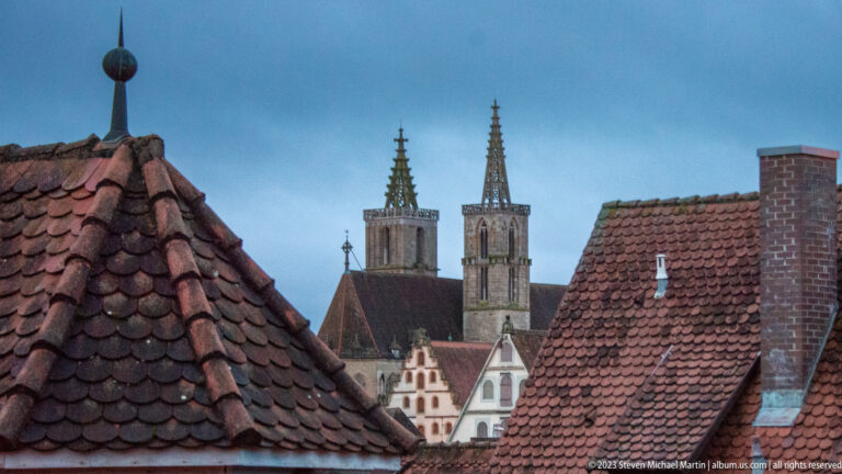 Twin Gothic towers of St. James Church rising above steep red-tiled rooftops and chimneys in Rothenburg's old town.