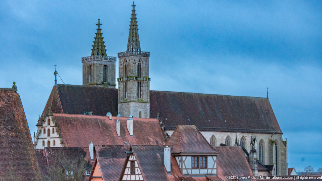 St. James Church with twin Gothic towers and long nave rising above tiled roofs and half-timbered houses.