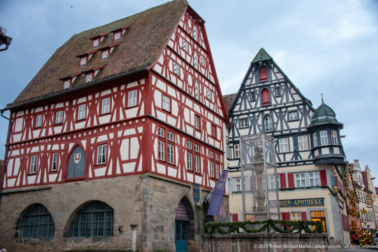 Red and dark half-timbered houses with steep tiled roofs, including the building marked “Marien-Apotheke.”