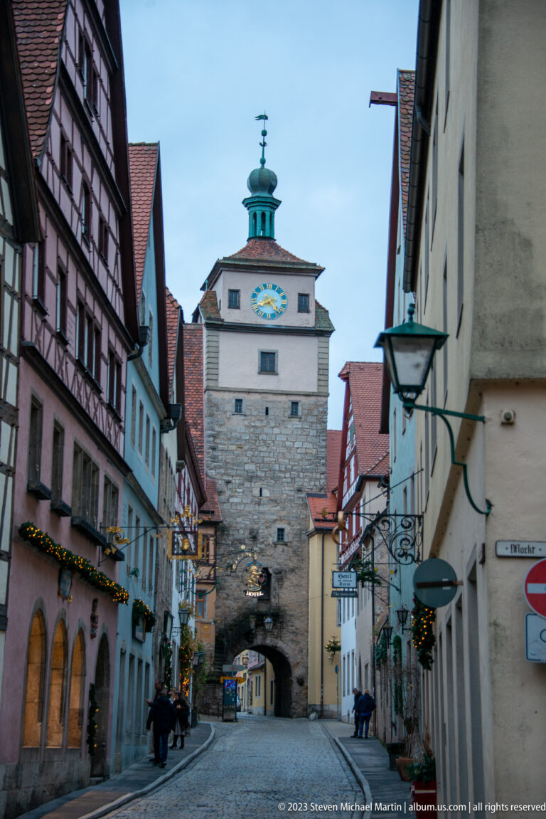 Markusturm with clock face and arched Röderbogen passage at the end of a narrow street lined with historic houses.