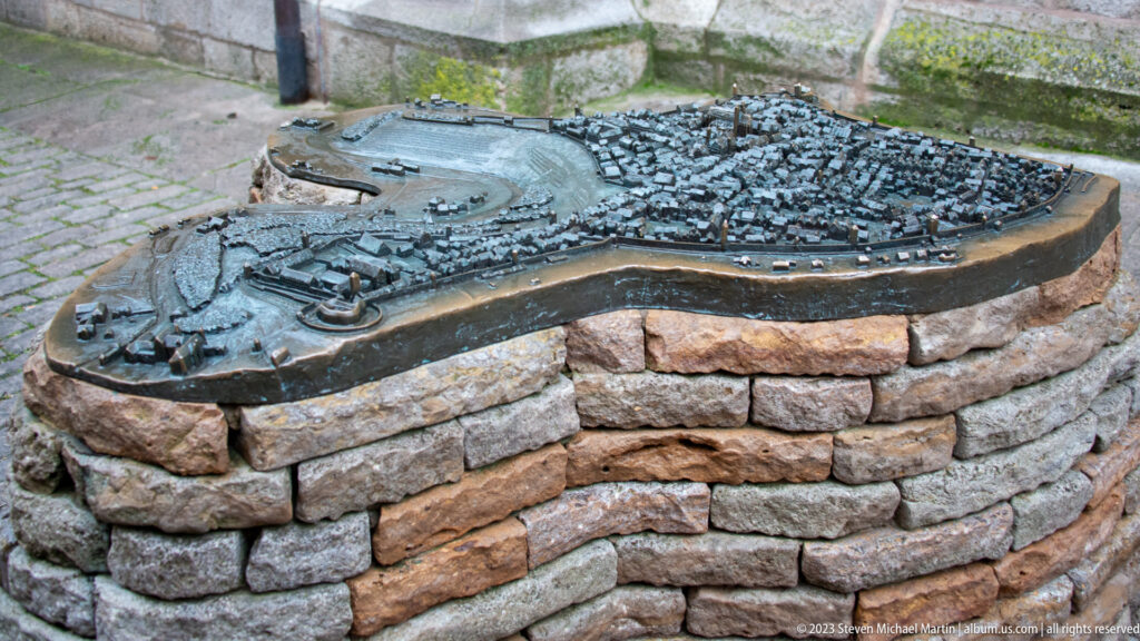 Bronze tactile model of Rothenburg showing miniature buildings, streets, towers, and the enclosing fortification wall on a stone base.