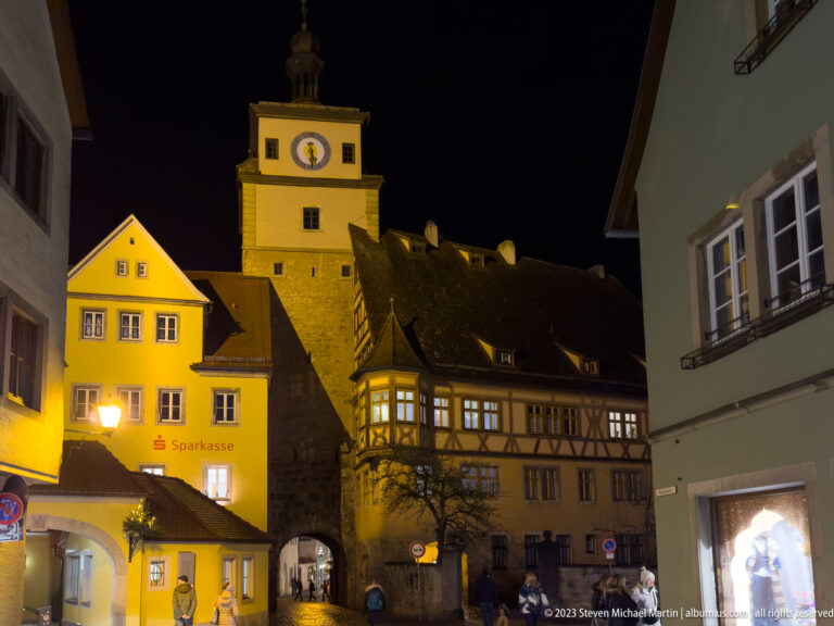 Illuminated Markusturm and Röderbogen above an arched passage, surrounded by half-timbered and plastered old-town buildings.