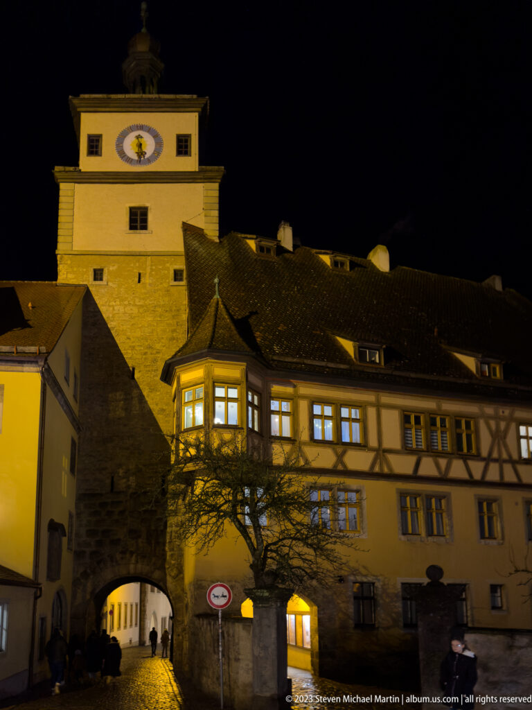 Markusturm and Röderbogen at night, with an arched passage and long half-timbered building across the foreground.