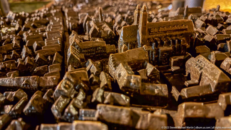 Close-up of a bronze tactile city model with miniature roofs, church forms, towers, and tightly packed streets.